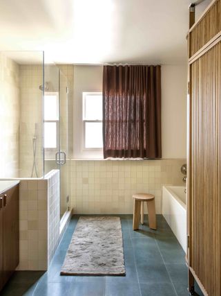 The bathroom with grey tiles, rust coloured curtains and a bespoke wooden panel