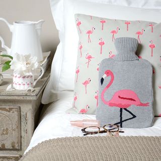 hot water bottle with white walls and bed with cushions