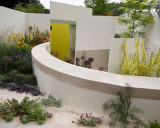 modern garden design with sand and low wall and planting