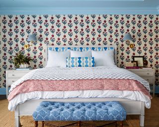 bedroom with blue ceiling, blue and red floral wallpaper, blue ottoman and white bedding with blue and red accents