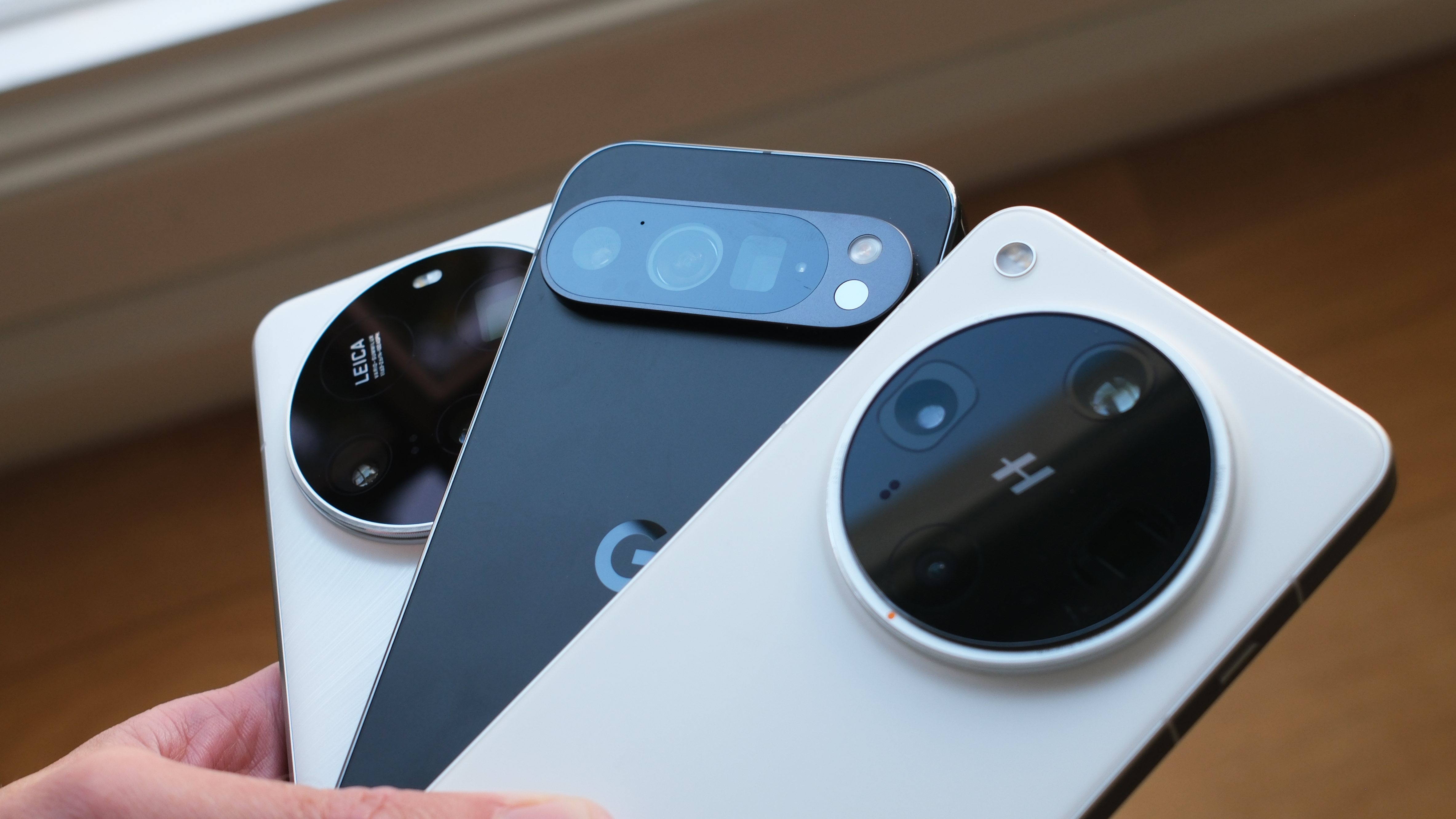 Google Pixel 9 Pro, Oppo Find X8 Ultra, and Xiaomi 15 Ultra phones all held in a hand