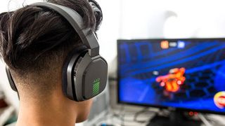 Man wearing Astro A10 gaming headset with a PC monitor in the background 