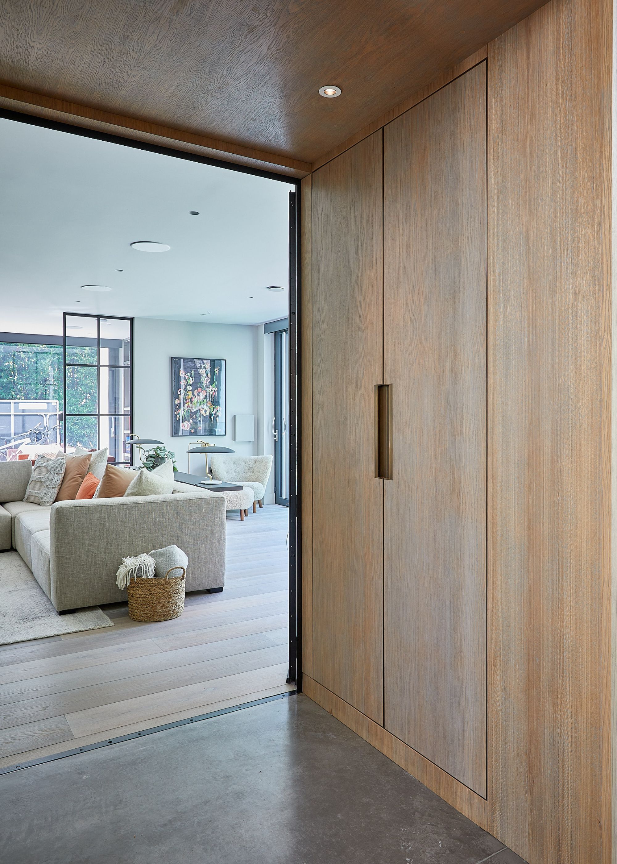 modern entryway with built-in wooden storage, leading into modern living room