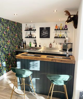 bar in garage conversion with wooden and stainless steel worktop, green glad bar unit, green wallpaper and green bar stools