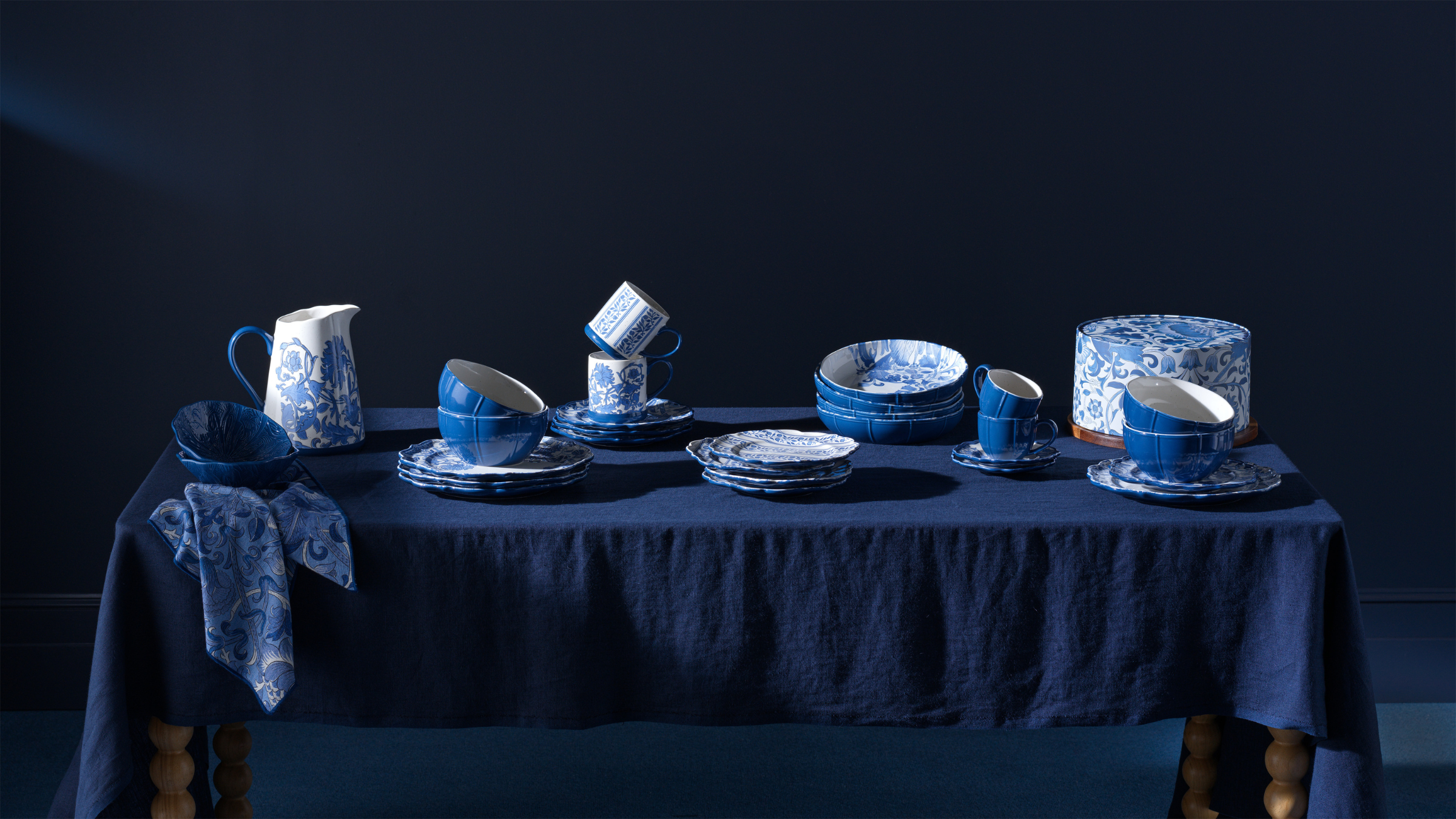 Habitat x Morris &amp; Co kitchen wear on table with indigo tablecloth and indigo wall behind it.
