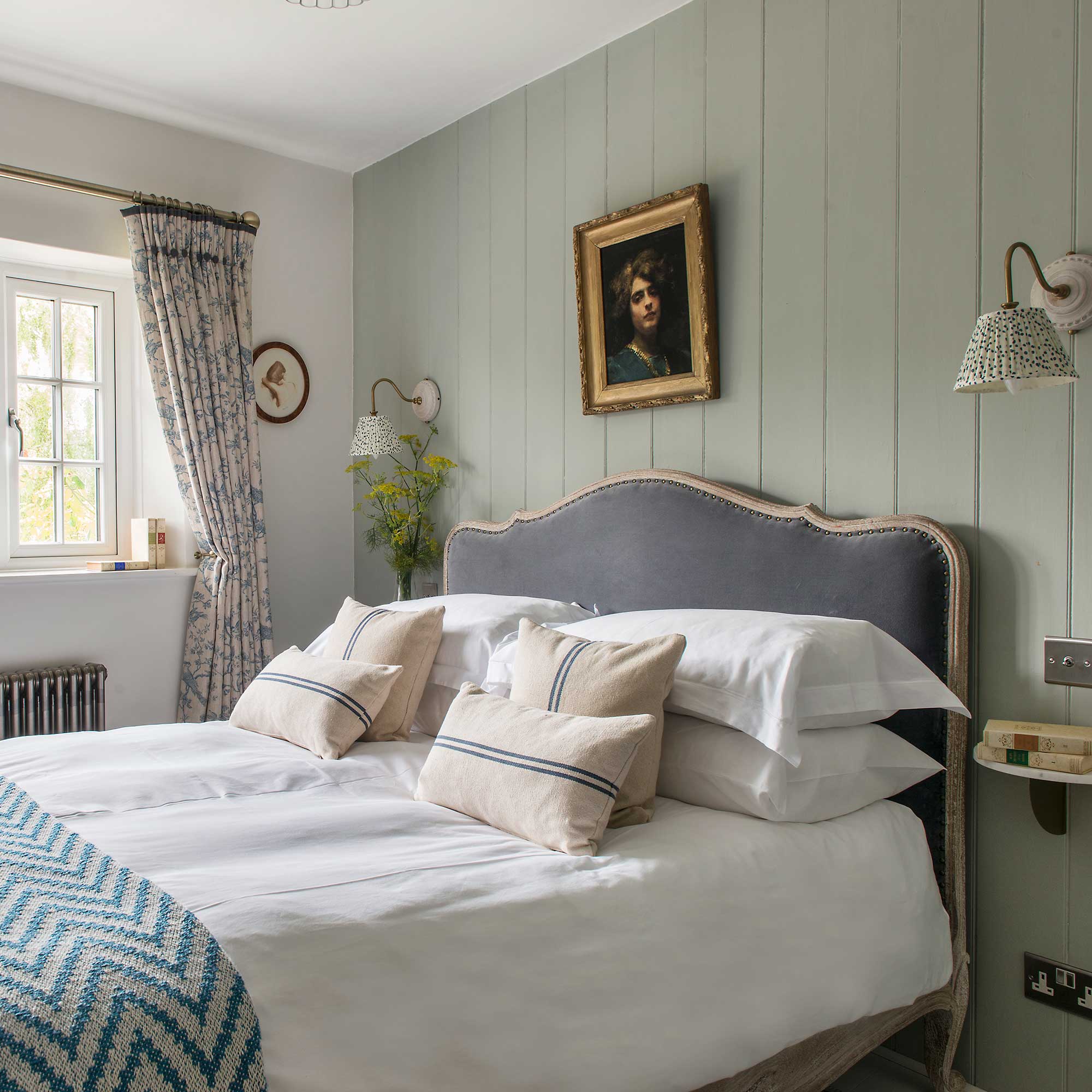 green panelled walls and upholstered bed in cottage bedroom