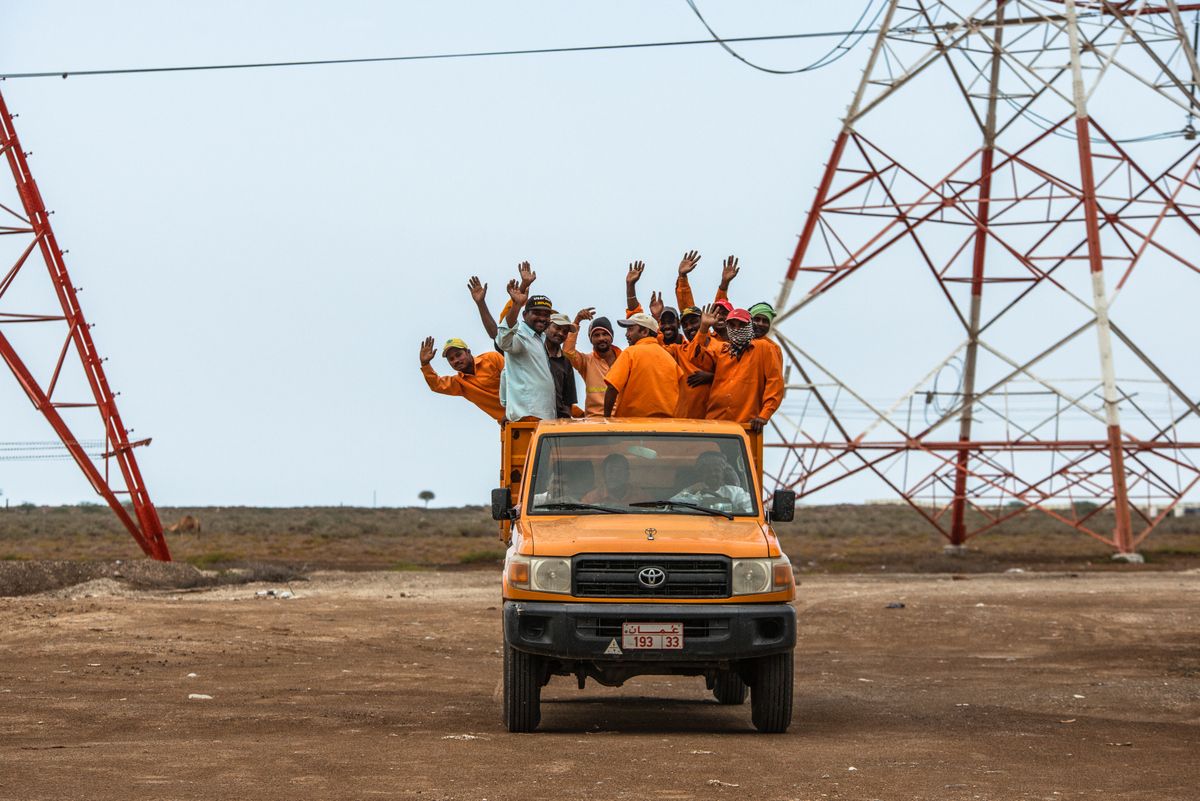 Some workers take a brief break to watch the peloton pass by