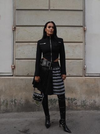 woman wearing pleated plaid skirt with black over the knee boots with black jacket