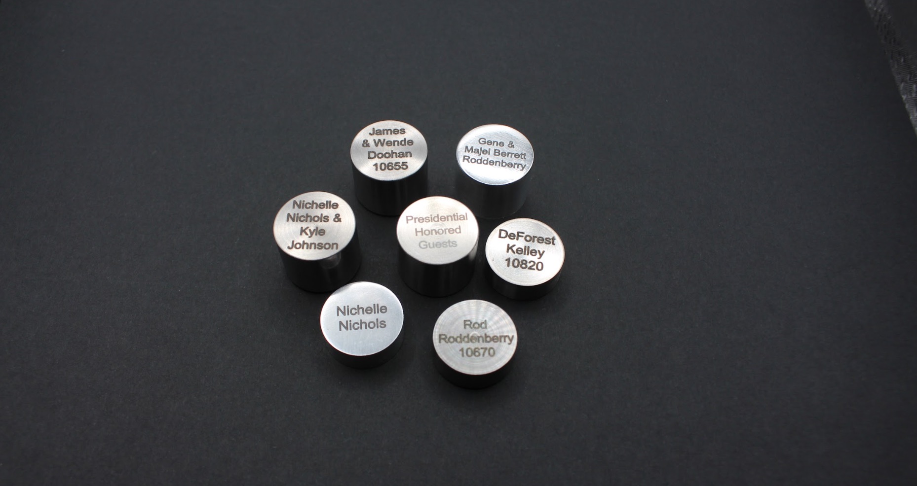 seven small metal capsules with the names of Star Trek cast and crew members