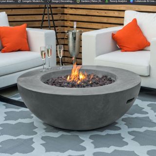Best fire pit cut out with fire on terrace rug and chairs with orange cushions