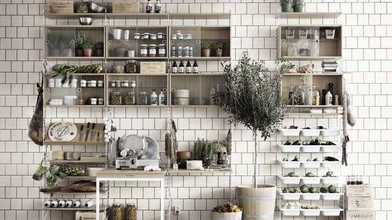 open shelving in the kitchen with jars and trays and a table