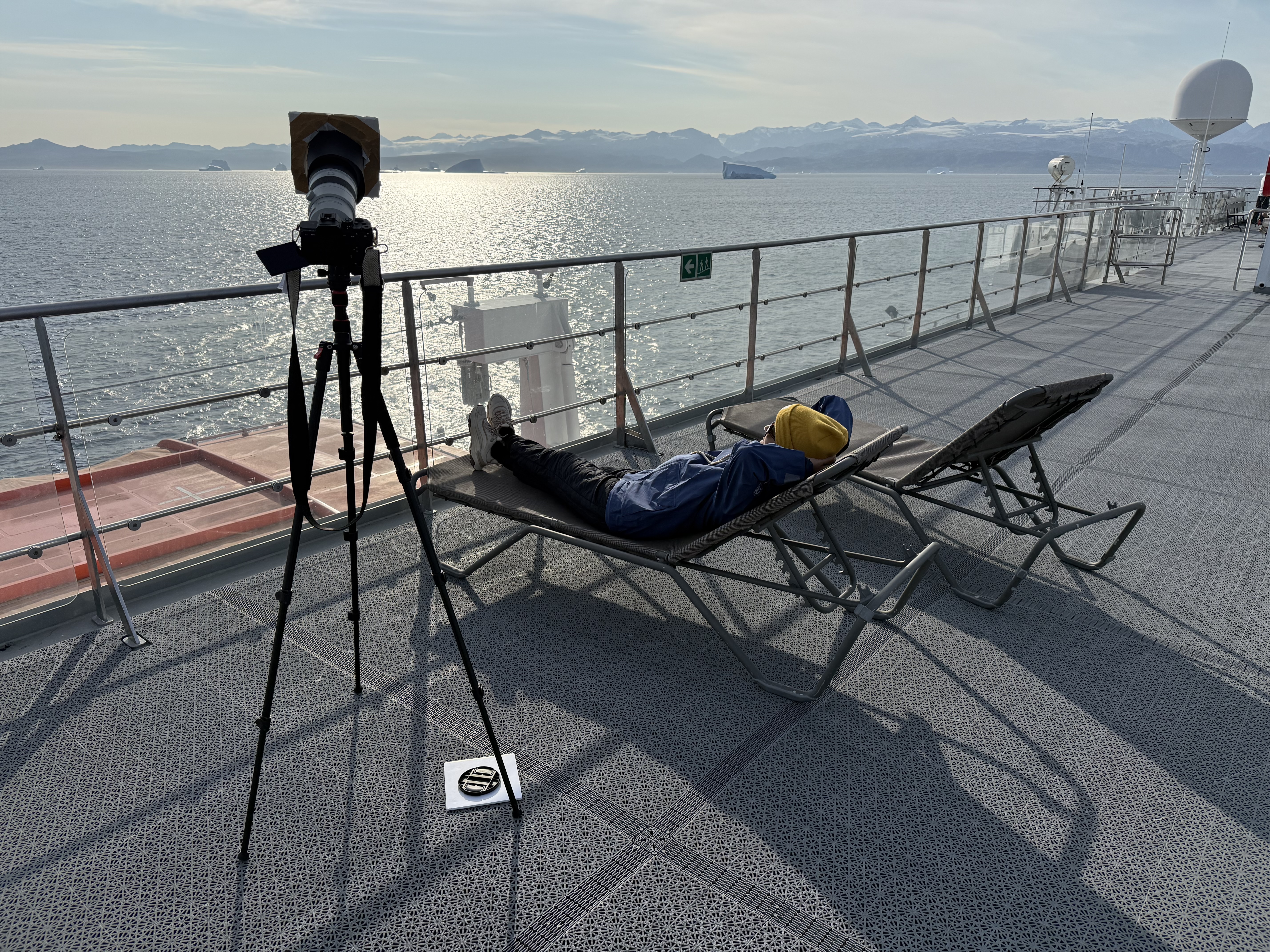 A person lies on a sun lounger watching the sun.