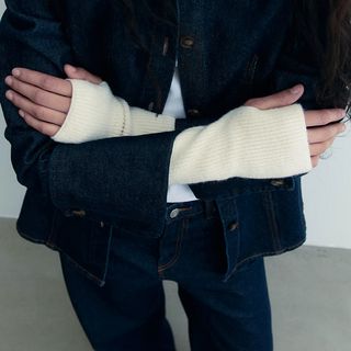 woman wearing cream fingerless gloves with a black jacket and jeans