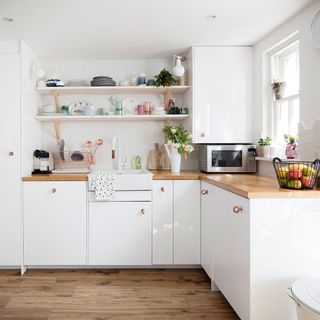 kitchen with white wall white cabinets wooden counter and wooden flooring