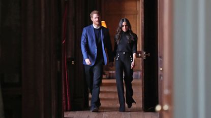 Prince Harry and Meghan Markle walk through the corridors of the Palace of Holyroodhouse on their way to a reception for young people at the Palace