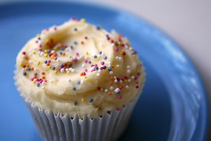A close-up of a gluten-free cupcake with sprinkles and buttercream