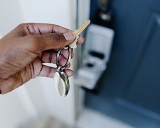 hand holding keys to front door of a house