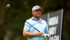 Graeme McDowell hits a tee shot and watches its ball flight