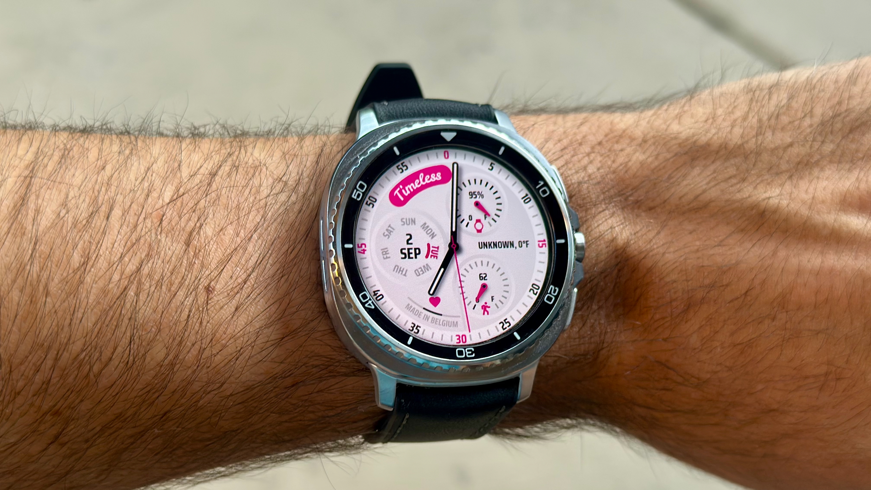 The Samsung Galaxy Watch 8 Classic on a person's wrist, showing a custom watch face from the Pujie app called "Timeless."