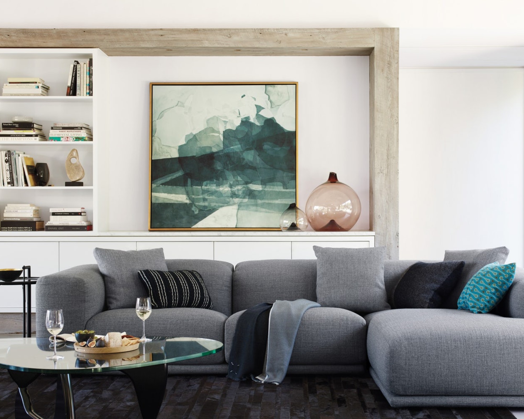 A grey sectional sofa in a modern white living room with abstract art on the wall