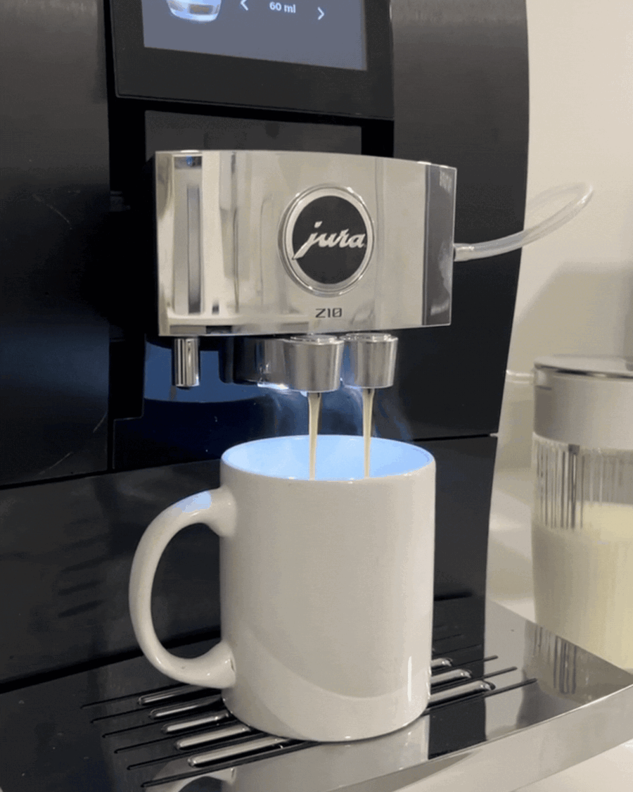 GIF of a black and silver Jura coffee machine brewing coffee into a white coffee mug