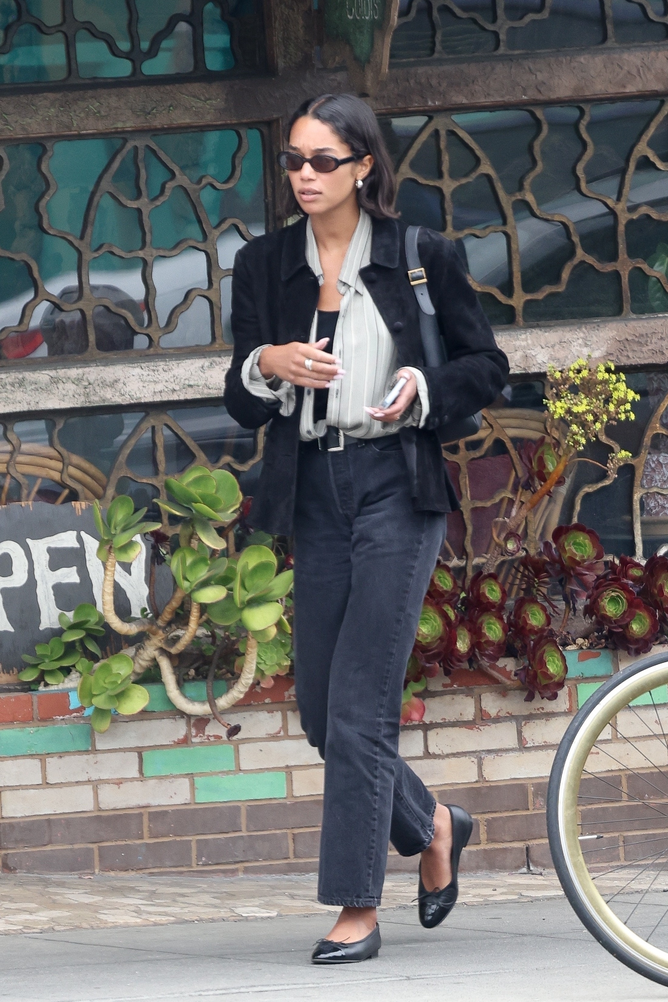 Laura Harrier wears black jeans with ballet flats.