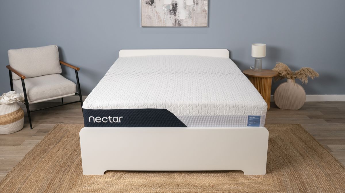 The Nectar Classic Memory Foam Mattress placed on a white wooden bedframe in a blue bedroom at our testing facility