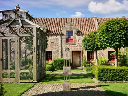 Fig 1: The courtyard garden, with its aviary and the front door of the house. Broadwoodside, East Lothian, photographed by Paul Highnam for Country Life. ©Country Life