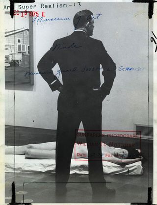 Vintage mid-century press photo featuring a crime scene. A man in a suit standing next to the body of a female model. The photo have markings on the back