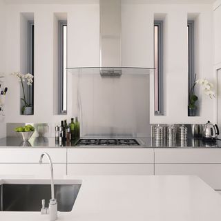 white kitchen with glass and stainless steel extractor