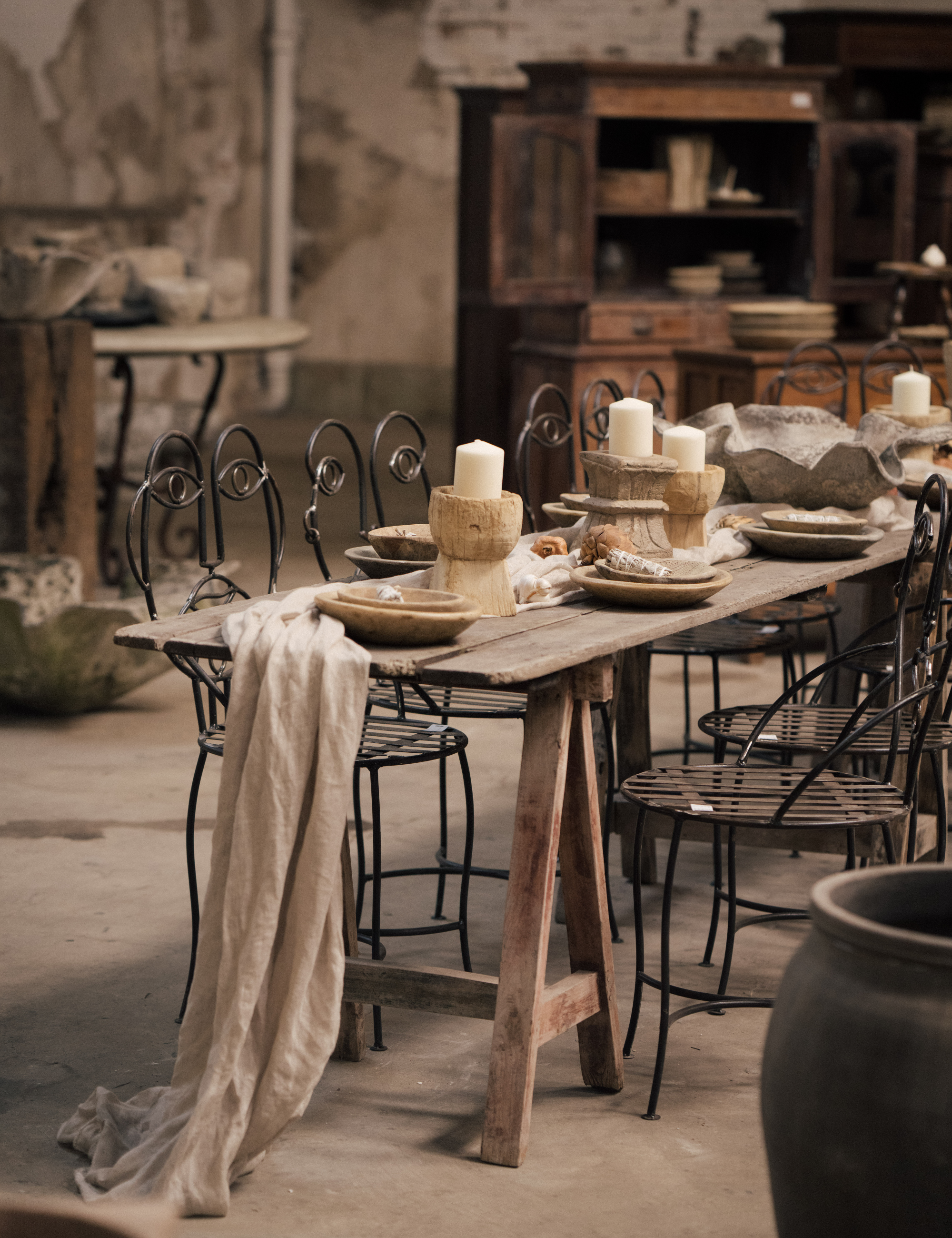 Olive Ateliers' LA showroom, featuring a long antique wooden dining table styled with surrealist iron dining chairs