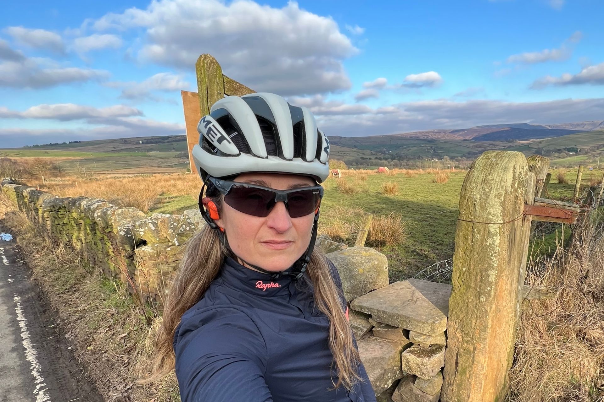 The Oladance open ear headphones worn by the writer on a ride with green hills in the background