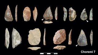 An array of stone tools against a black background.