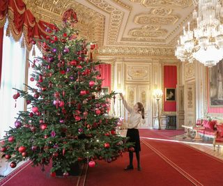 Staff hanging baubles on the tree in the crimson drawing room in Windsor
