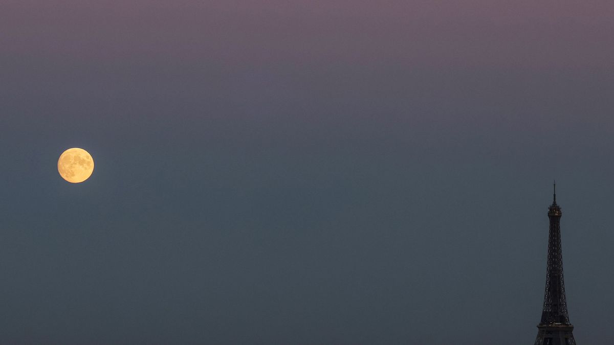 The full moon rises on the side of the Eiffel Tower in Paris, on October 8, 2022.