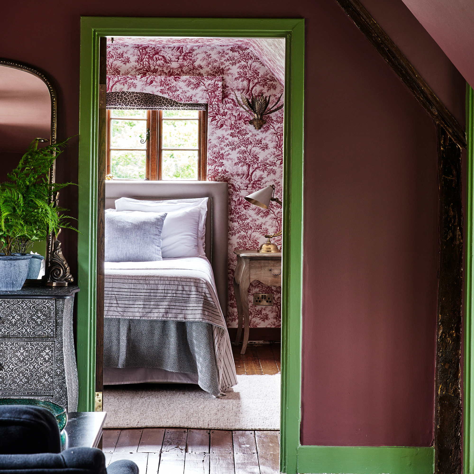 Attic bedroom with toile wallpaper and dressing room painted burgundy with green woodwork