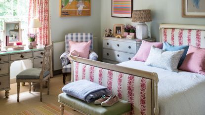 Kids' room ideas in a pale gray-green bedroom with dressing area and pink and white upholstered bed and drapes.