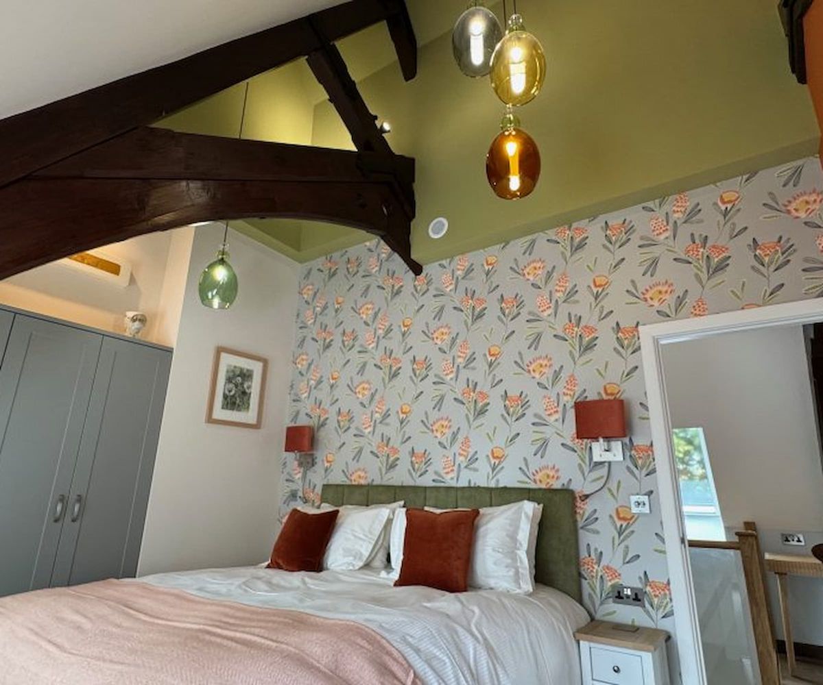 A bedroom with in-built wardrobes and flower pattern wallpaper
