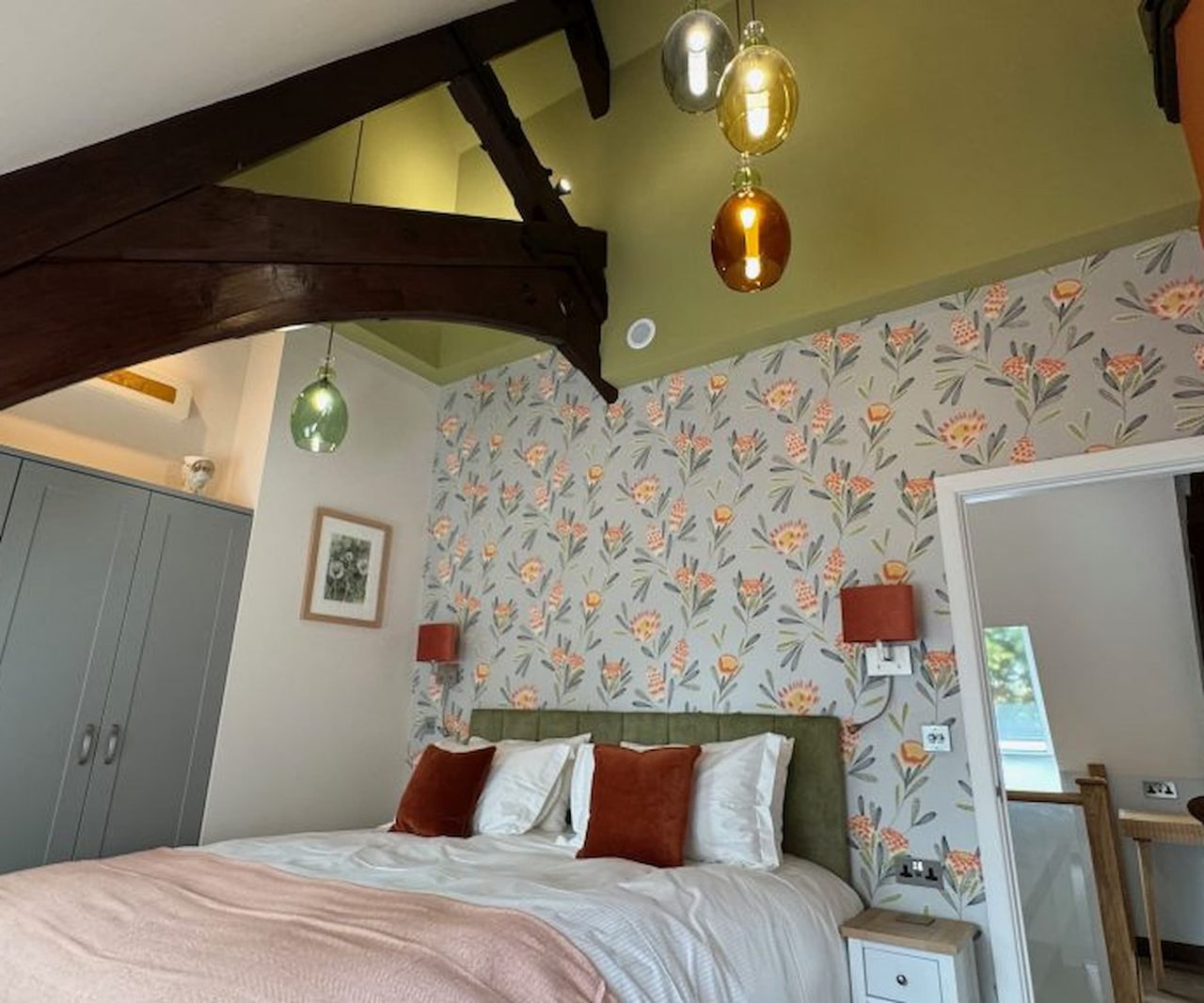 A bedroom with in-built wardrobes and flower pattern wallpaper