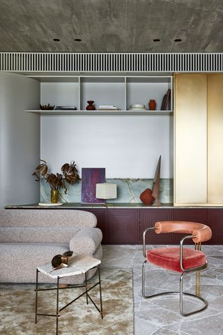 a cinema room with a purple sideboard red chair and brass cabinet with green marble