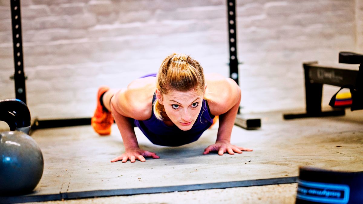 Woman performs push-up in a garage