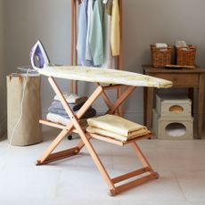 room with iron table and iron with duvet and clothes and clothes box