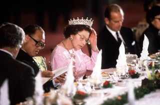 Queen Adjusting Her Tiara Whilst Reading The Menu Before Dinner Is Served
