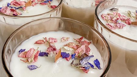 a close up of handmade candles in glasses with dried flowers