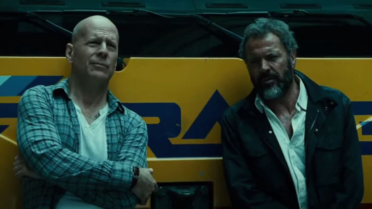 John McClane and Kamarov leaning against a bus in A Good Day to Die Hard