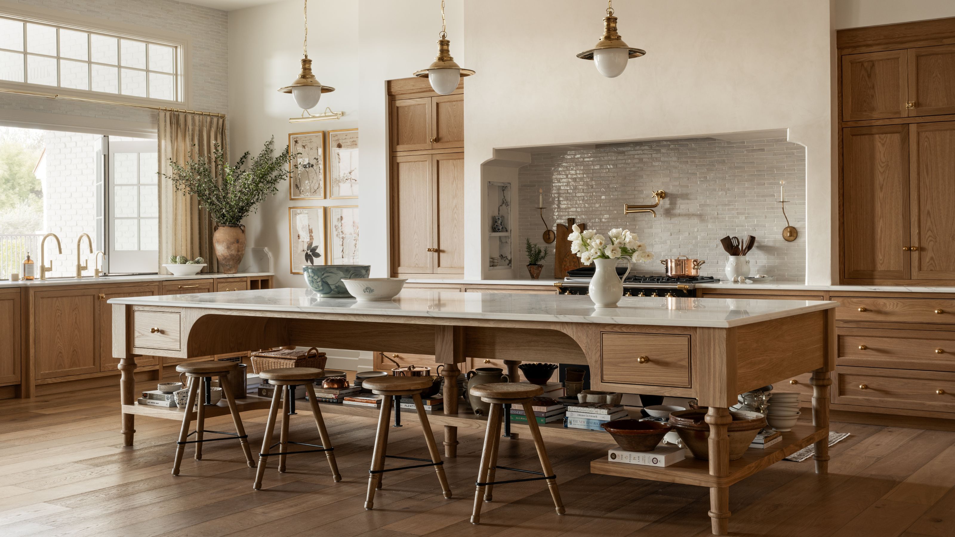 a large open oak kitchen with a huge wooden island with open shelving storage, large shaped cooker, huge window with the sink below and vintage decor