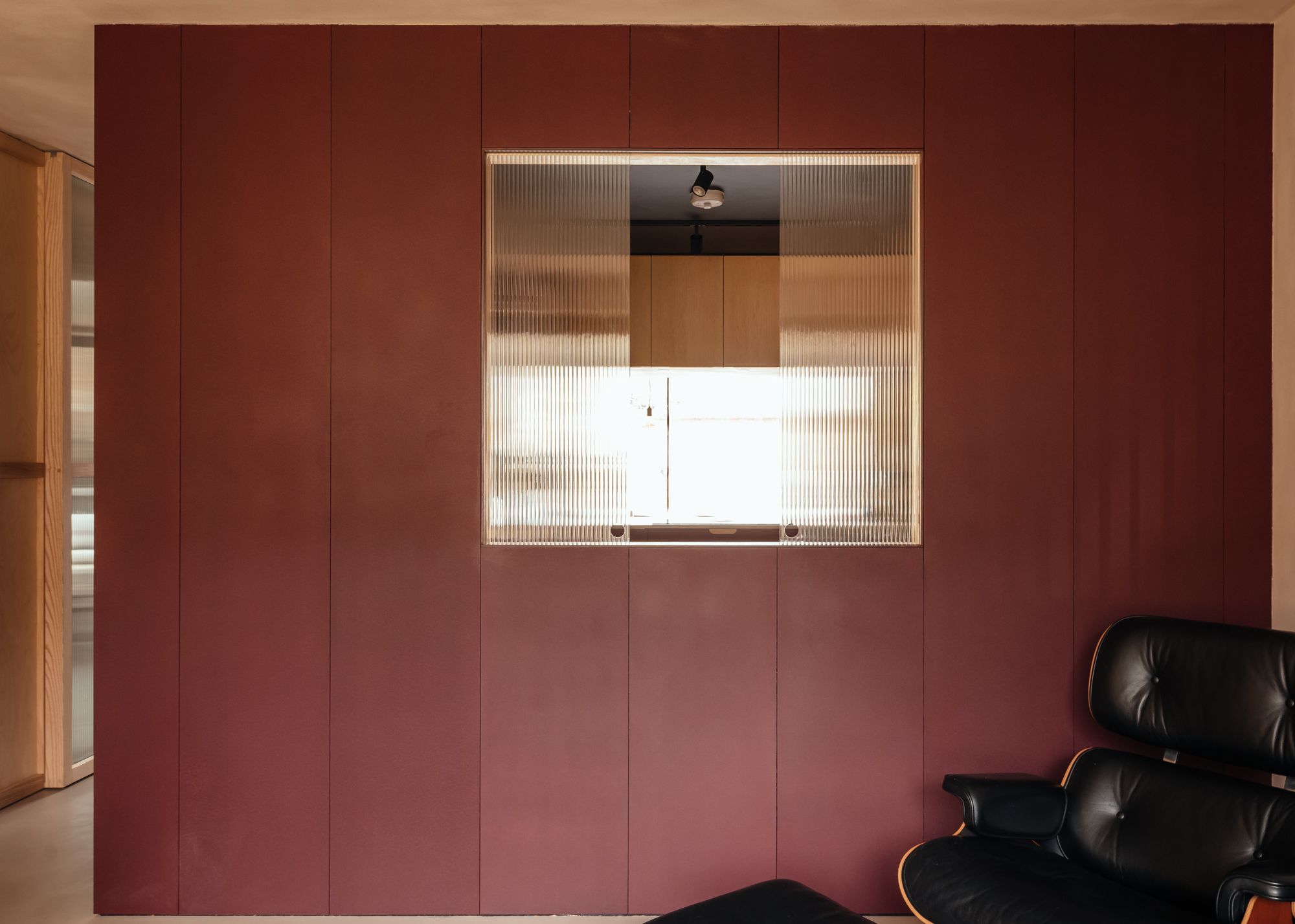 A kitchen painted red, with a hatch in reeded glass