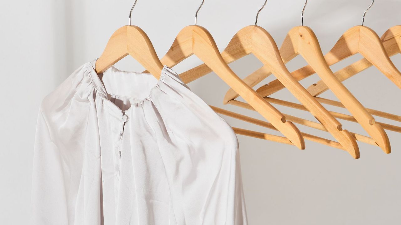 silk-look white shirt hanging on a wooden hanger close-up. 