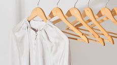 silk-look white shirt hanging on a wooden hanger close-up. 