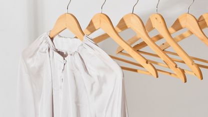 silk-look white shirt hanging on a wooden hanger close-up. 